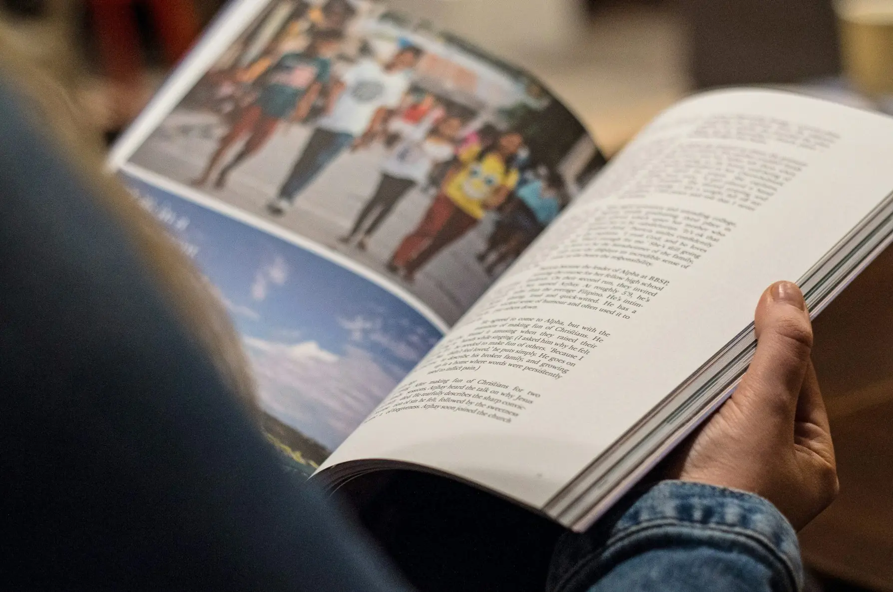 person in blue denim top reading book